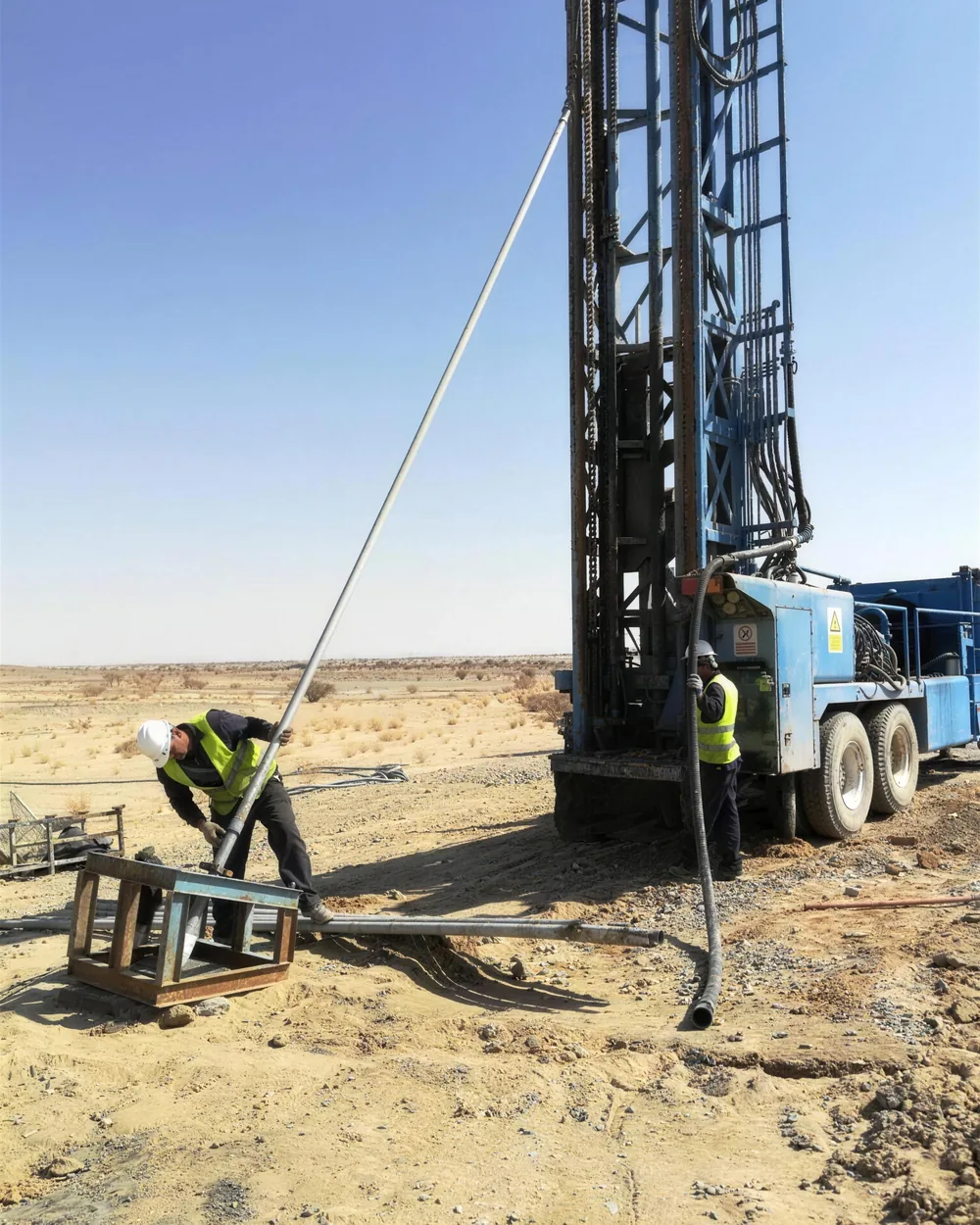 Crew handling drill rods at a water-well rig