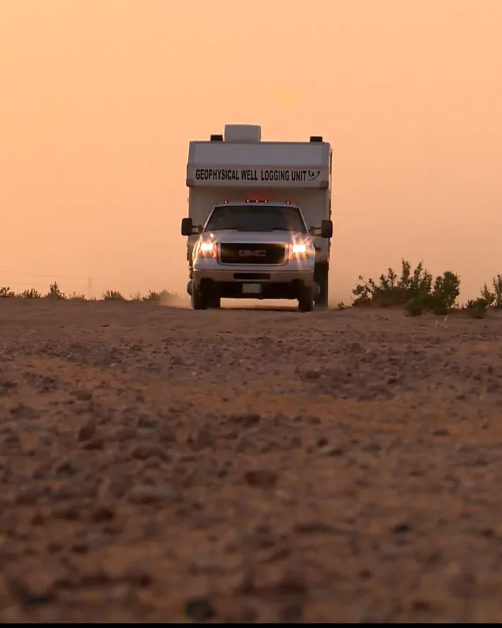 Well-logging truck parked on open ground at sunset