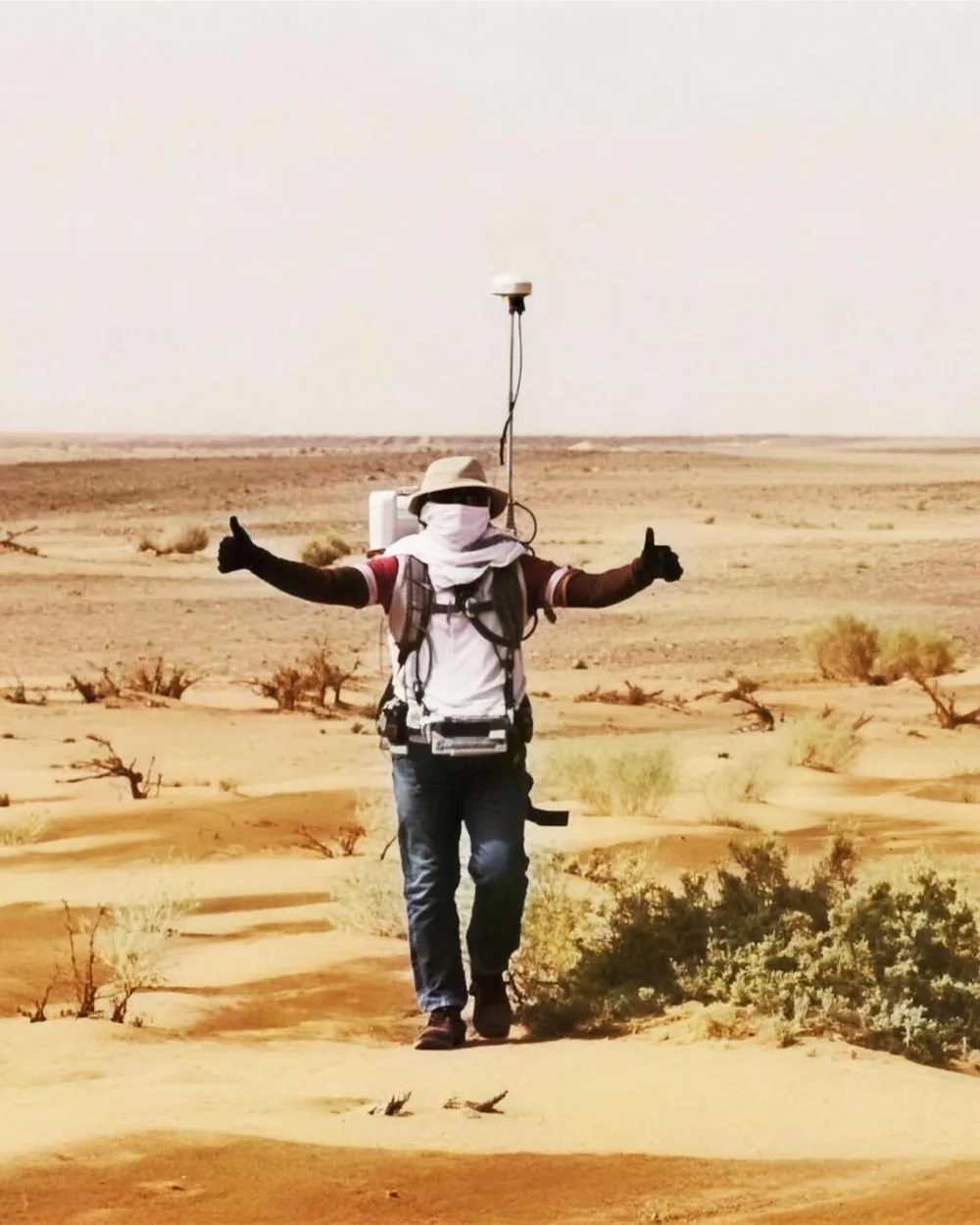 Surveyor carrying a GNSS receiver across the desert