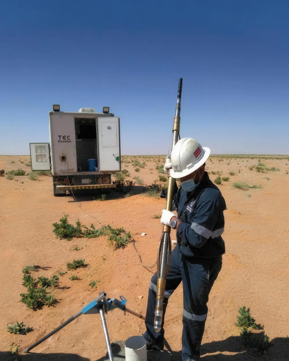 Operator running a logging probe into a well beside the logging unit