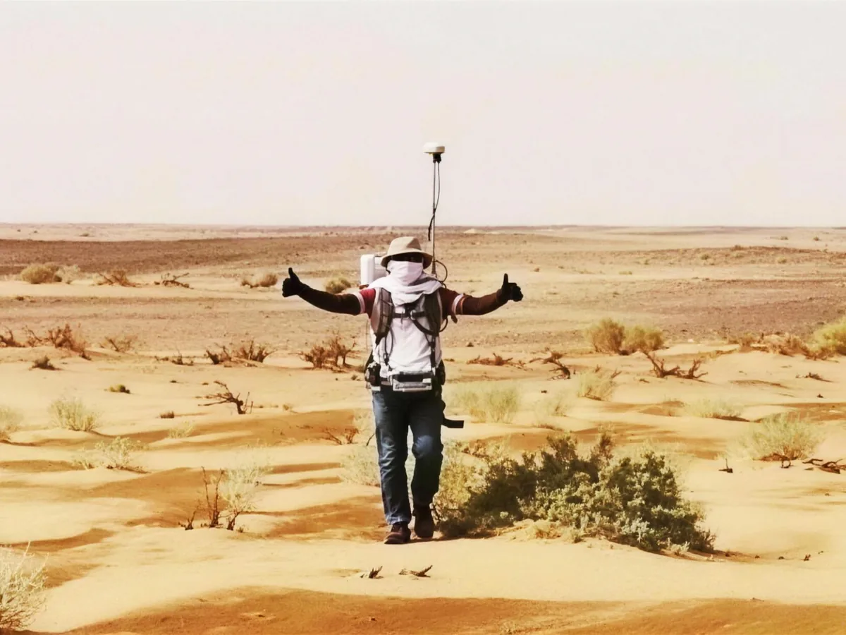 Surveyor carrying a GNSS receiver across the desert